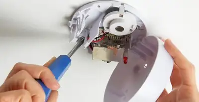 Certified technician wiring smoke detector during installation in Baton Rouge, LA